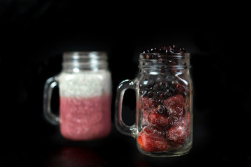 Summer berry cocktail with chia seeds in vegetable milk in glass glasses on a dark background.
