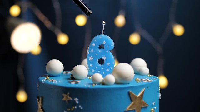 Birthday cake number 6 stars sky and moon concept, blue candle is fire by lighter and then blows out. Copy space on right side of screen if required. Close-up and slow motion
