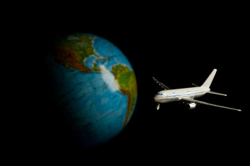 avia transportations concept. airplane on a black background on a background of the globe. flight to any point of the world