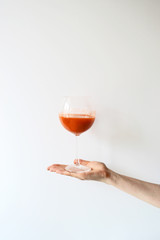 Hand holding glass of carrot juice. Fresh juice on glass isolated on white background