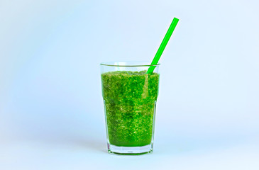 Green detox smoothie with a straw on blue background. 