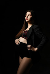 Young beautiful slim pregnant woman with long hair in posing on black background. Pregnancy motherhood, new born life expectation