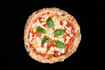 real italian pizza margherita on a black background from the top - obrazy, fototapety, plakaty