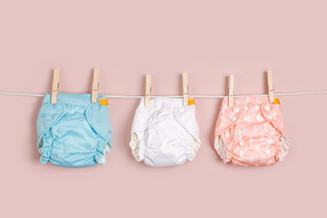 Reusable cloth baby diapers drying on a clothes  line. Eco friendly cloth nappies on a pink background. Sustainable lifestyle. Zero waste concept. - obrazy, fototapety, plakaty
