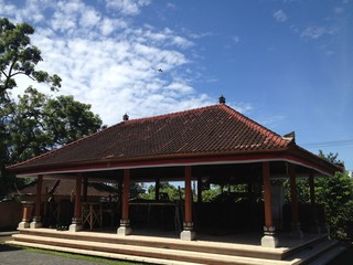 Fototapeta na wymiar Un complejo de templos abiertos con un gran techo de tejas en el pueblo. Día despejado y soleado. Indonesia, Bali