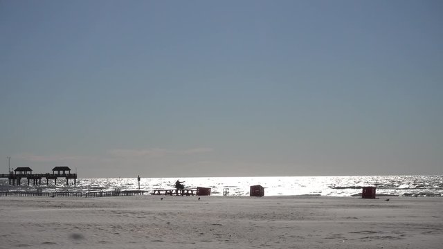 Seagulls Flying On Beach With Two Girls By Pinic Table In Distance