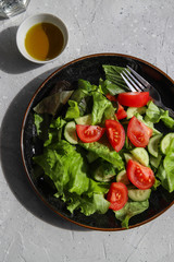 Fresh summer vegetable salad with tomatoes, cucumber, lettuce and olive oil. Healthy food for vegetarian or vegan