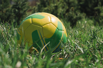 Fototapeta premium yellow ball lying on the green grass, soccer ball, football