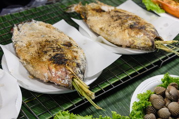 Salted fish with lemongrass being cooked on a barbeque grill at a street food stall, Bangkok, Thailand