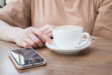 On the table a woman's hand, a Cup of coffee and phone. Mock up. Cooking, food delivery, cafe, restaurant, cheese Factory, cheese tasting