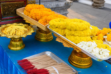 Garlands of orange and yellow chrysanthemum flowers with incense at a Buddhist temple, Bangkok,...