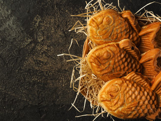 traditional japanese dessert tayaki. sweet waffles in the form of fish with different fillings. top view  a dark background. Black slate dishes