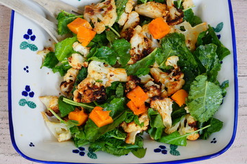 Fresh green kale salad with roasted butternut squash and cauliflower