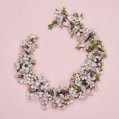 Round frame wreath made of spring flowers on pink background. Top view. The concept of spring and March 8. Square photograph