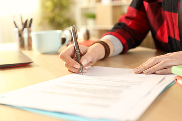 Student girl hands signing contract on a desk