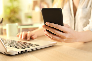 Woman hands checking phone using laptop
