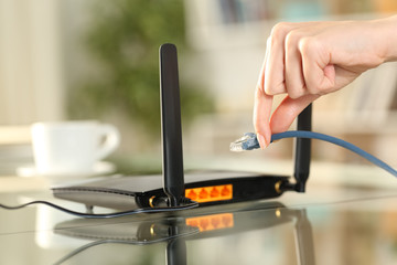 Woman hands plugging ethernet cable to router - obrazy, fototapety, plakaty