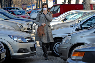 Fototapeta premium Milan - Italy november 6,2018 - smog and atmospheric pollution, pm 10 - girl with antismog mask in the city in urban traffic - mask anti n-cov19 coronavirus outbreak epidemic