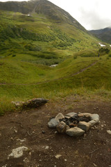 Stone fire pit on dirt pad in alaskan apline valley - 335897127
