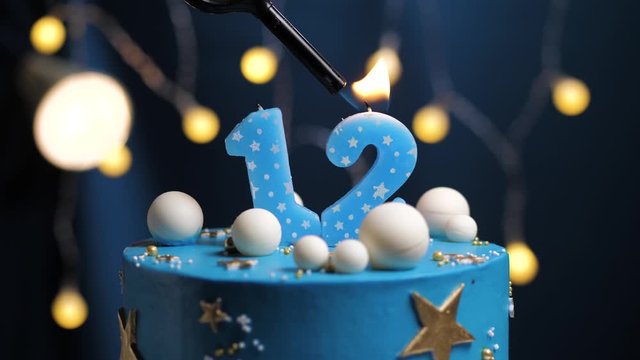 Birthday cake number 12 stars sky and moon concept, blue candle is fire by lighter and then blows out. Copy space on right side of screen if required. Close-up and slow motion
