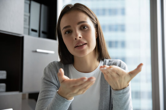 Headshot of young female employee look at camera have video call at workplace in office, millennial woman worker talk speak with client customer on web conversation use wireless Internet connection