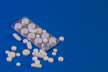 white pills and capsules blister with pills on a blue background. copy space