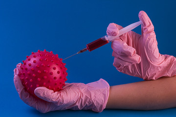 coronavirus vaccine. Syringe with a needle with a vaccine in hands in pink gloves from coronavirus on a blue background