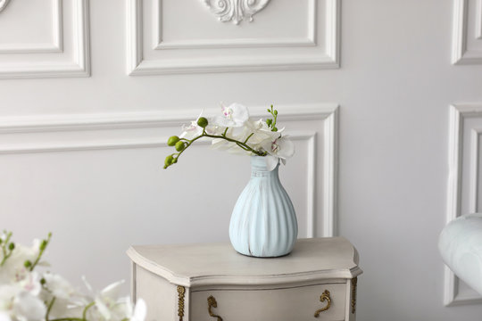White orchid flowers in vase on table. vintage vase with orchid at home on chest of drawers.