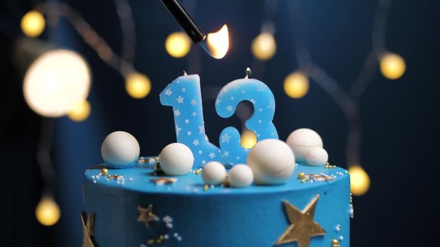 Birthday cake number 13 stars sky and moon concept, blue candle is fire by lighter and then blows out. Copy space on right side of screen if required. Close-up and slow motion