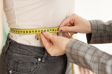 Female Designer's Hands Measuring Young Woman's Waist