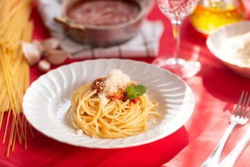 Piatto di spaghetti con sugo rosso, parmigiano grattugiato e basilico