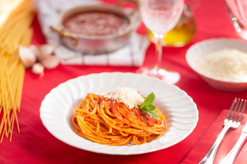
Spaghetti cotti conditi con la salsa di pomodoro, parmigiano grattugiato e basilico nel piatto
