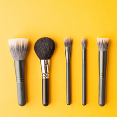  Professional makeup brushes top view on a yellow background with place for text. Skin care. Flatlay.