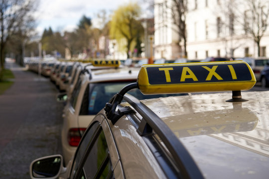 Berlin Germany, Line Of Yellow Taxi Cabs Parking In A Street In Inner City Of Berlin. No Passengers Because Of Missing Tourists, Closup Taxi Sign