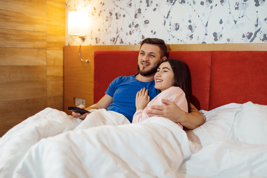 Love couple lying in bed and watching TV