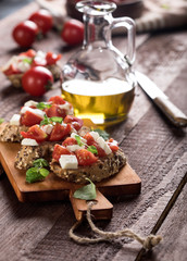 Bruschetta with tomatoes, mozzarella cheese and basil on wooden background.