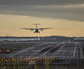 Fototapeta na wymiar Airplane landing to airtport runway at sunset