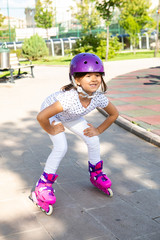 Little girl on roller skates in helmet at park