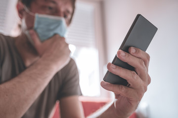 Worried man using mobile phone in home quarantine self-isolation