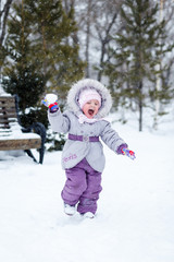Fototapeta na wymiar little girl plays snowballs in the park