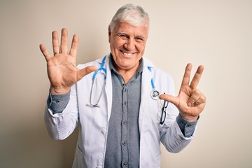 Naklejka premium Senior handsome hoary doctor man wearing coat and stethoscope over white background showing and pointing up with fingers number eight while smiling confident and happy.