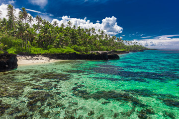 Tropical beach on south side of Samoa Island with coconut palm trees