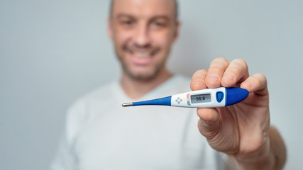 Healthy Man Showing Thermometer With Normal Temperature Over Gray Background