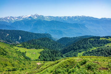 View over the Green Valley, surrounded by high mountains with snow on a clear summer day.