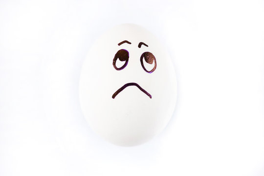 Sad face drawn on white Easter egg