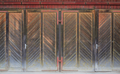 Several old doors made of brown wood form a large area that is weathered and form the entrance to several rooms