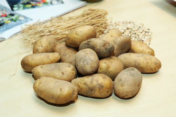 Bunch of potatoes on wooden background close up shoot . Fresh potatoes in an old sack on wooden background. Free place for text. Top view . potatoes on an old wooden table .