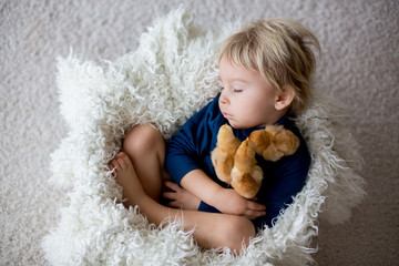 Cute blond toddler boy, sleeping with newborn chicks