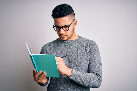 Young Handsome Smart Student Man Reading Book Over Isolated White Background With A Confident Expression On Smart Face Thinking Serious