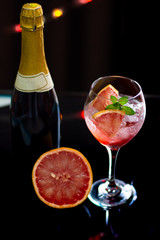 Refreshing and elegant gourmet cocktail next to a grapefruit and a bottle of wine at the bar